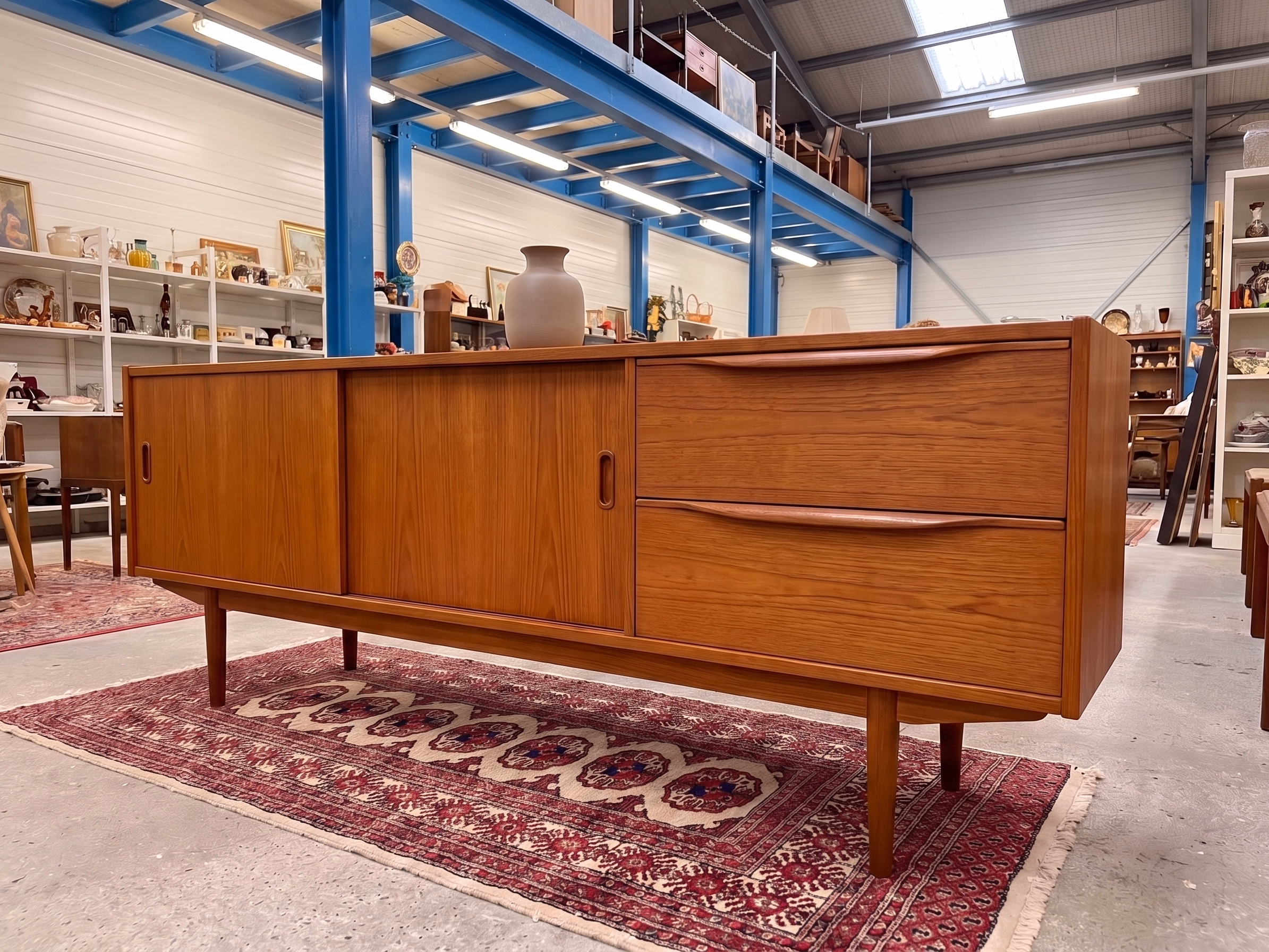 Teak-Sideboard mit zwei Schiebetüren und zwei Schubladen auf einem Perserläufer in der Halle